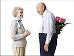 Older man with bouquet of pink roses behind back