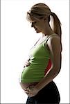 Profile of a pregnant woman touching her abdomen