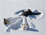 High angle view of a young woman lying in snow making a snow angel
