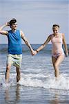 Young couple walking in the water on the beach
