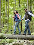 Low angle view of a young couple walking on a fallen tree