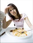 Portrait d'une jeune femme trop manger à la table