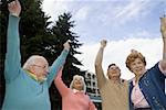 Low angle view of two senior couples laughing with their arms raised