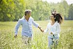 man and a woman holding hands and running in a field