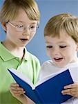 Two boys reading book