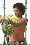 Jeune femme arranger les fleurs dans un vase