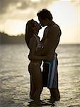 Young couple kissing at sunset in the ocean
