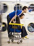 Young couple on trolley at Laundromat having fun