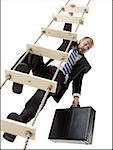 Low angle view of a businessman climbing a ladder holding a briefcase