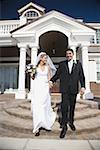 Newlywed couple walking down the steps in front of a building