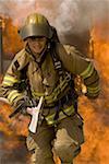 Firefighter running through fire holding an axe