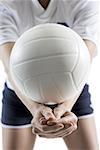 Mid section view of a young woman serving a volleyball