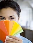 Portrait of a young woman holding color swatches in front of her face