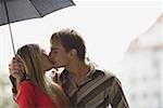 Gros plan d'un jeune couple baiser sous un parapluie