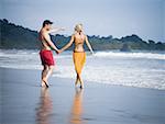 Mid adult couple holding hands and walking on the beach