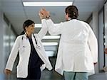 Rear view of a male doctor giving high-five to a female doctor