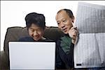 Close-up of a father holding a newspaper and his son using a laptop