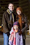Man with woman and girl standing outdoors in winter smiling
