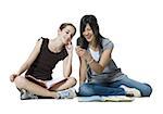 Two girls sitting cross legged with homework and mp3 player