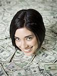 Porträt einer jungen Frau begraben unter einem Haufen von Papiergeld