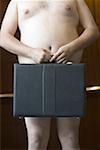 Mid section view of a naked businessman holding a briefcase