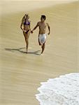 Erhöhte Ansicht eines jungen Paares, Hand in Hand und laufen am Strand