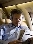 A senior man reading a magazine in an airplane