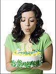 Close-up of a teenage girl blowing out candles on her birthday cake