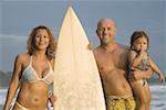 Portrait d'une famille tenant une planche de surf