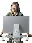 Girl standing behind computer monitor smiling