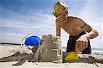 Low angle view of a young man digging sand on the beach