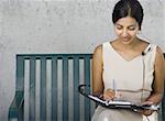 Businesswoman sitting on a bench and writing in a diary