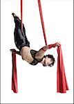 Male circus gymnast tangled in red drapes