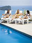 Three young women relaxing by the pool