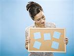 Close-up of a young woman holding a cork board