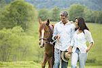 homme et une femme qui marche avec un cheval