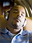 Close-up of a man listening to music on headphones in an airplane