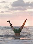 Low section view of a mature man doing a handstand in the sea