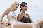 Two young women sitting on rock