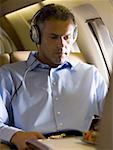 A businessman listening to music on headphones in an airplane