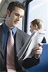 Close-up of a young man reading a newspaper on a commuter train