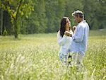 Profile of a man and a woman holding hands in a field