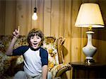 Boy on sofa with light bulb and lamp pointing up