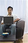 Man sitting on a sofa and using a laptop