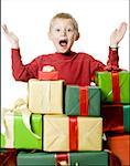 Portrait of a boy standing behind the stack of gifts with his arms raised