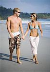 Young couple looking at each other and walking on the beach