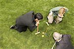 High angle view of two businessmen and a businesswoman playing croquet