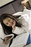 Close-up of a young woman reading sheets of paper holding a pen