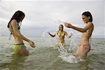 Three teenage girls splashing water in the sea