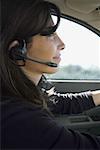 Close-up of a woman wearing a headset and driving a car